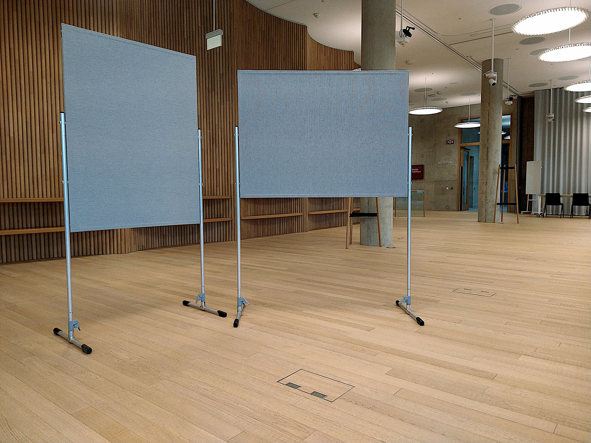 Two blank grey display boards on stands in a wood-panelled foyer